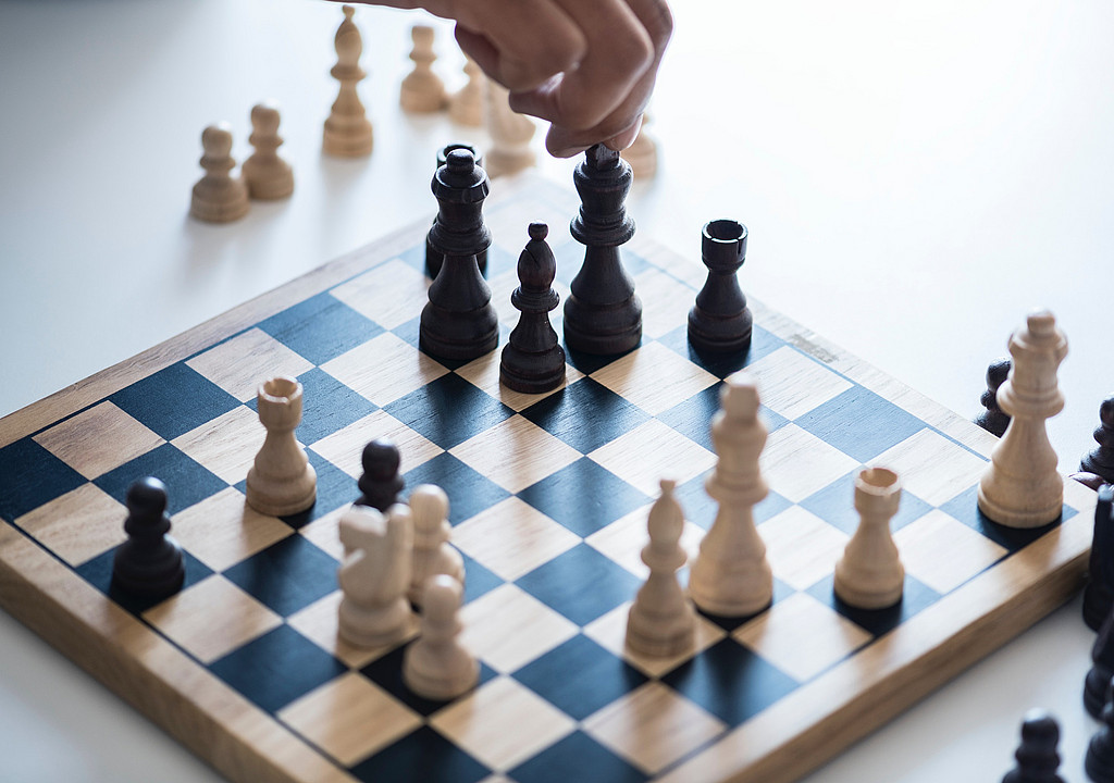 Close-up shot of a chess board. A hand is moving the black King.